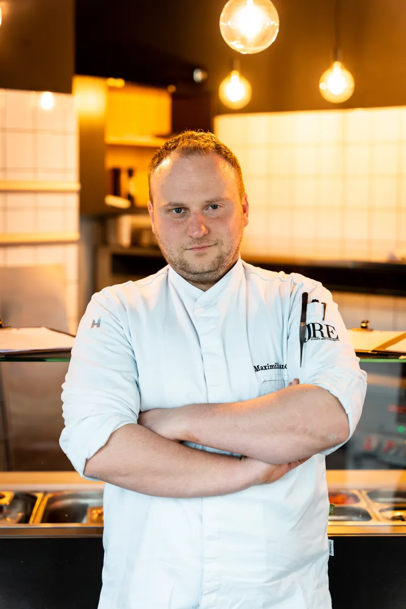 Sternekoch mit verschränkten Armen in seiner Küche
